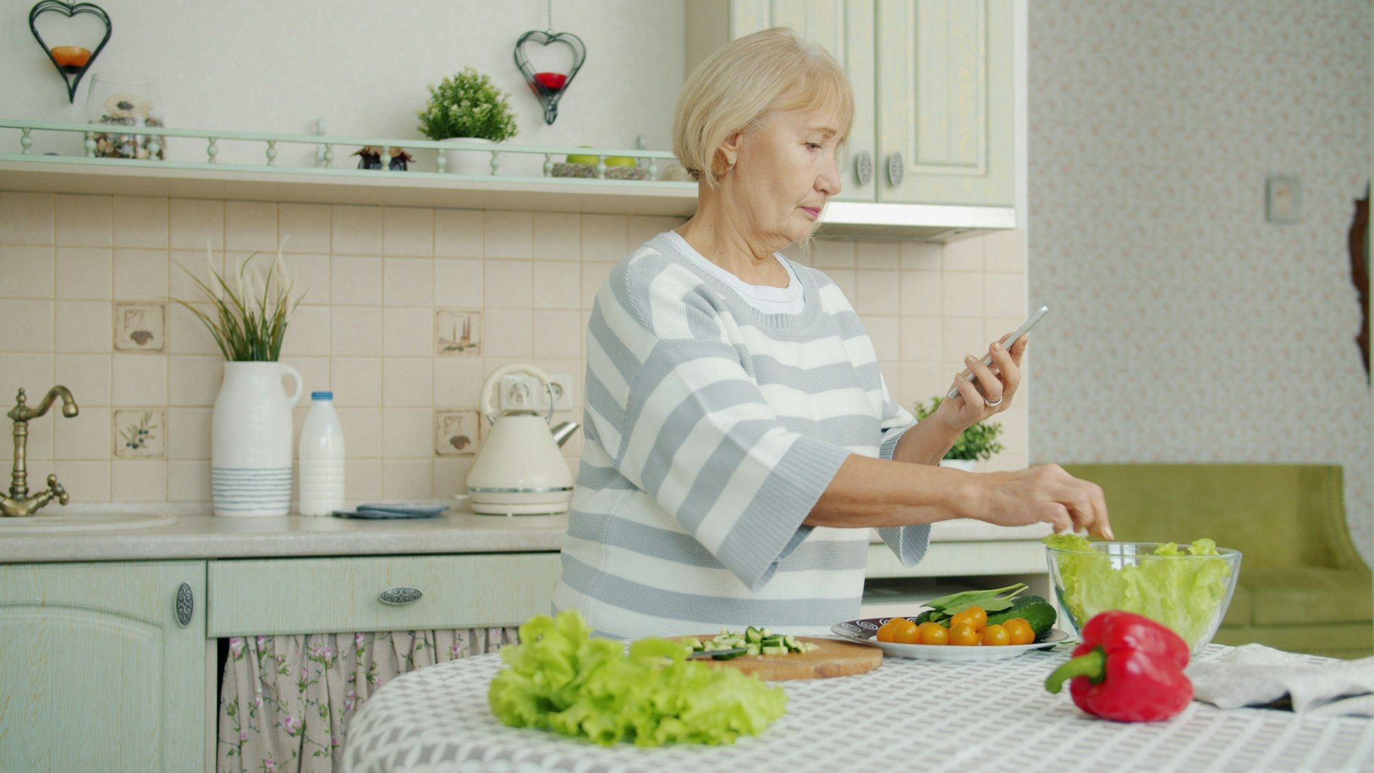 Eine ältere Frau bereitet in ihrer Küche einen Salat zu